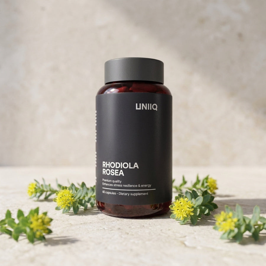 Uniiq Rhodiola Rosea kapsler sentrert på lys stein med gule rosenrot-blomster