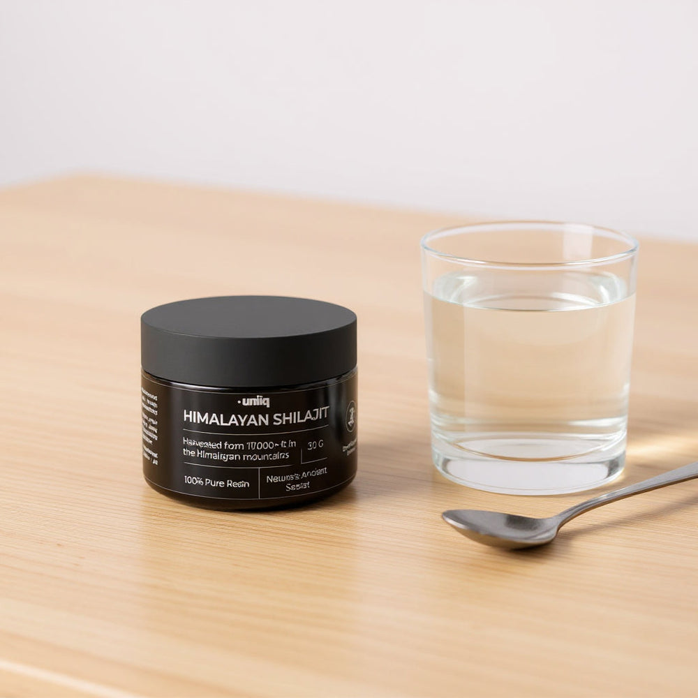 Himalayan Shilajit fra Uniiq ved siden av et glass vann og en skje, klar til dosering
